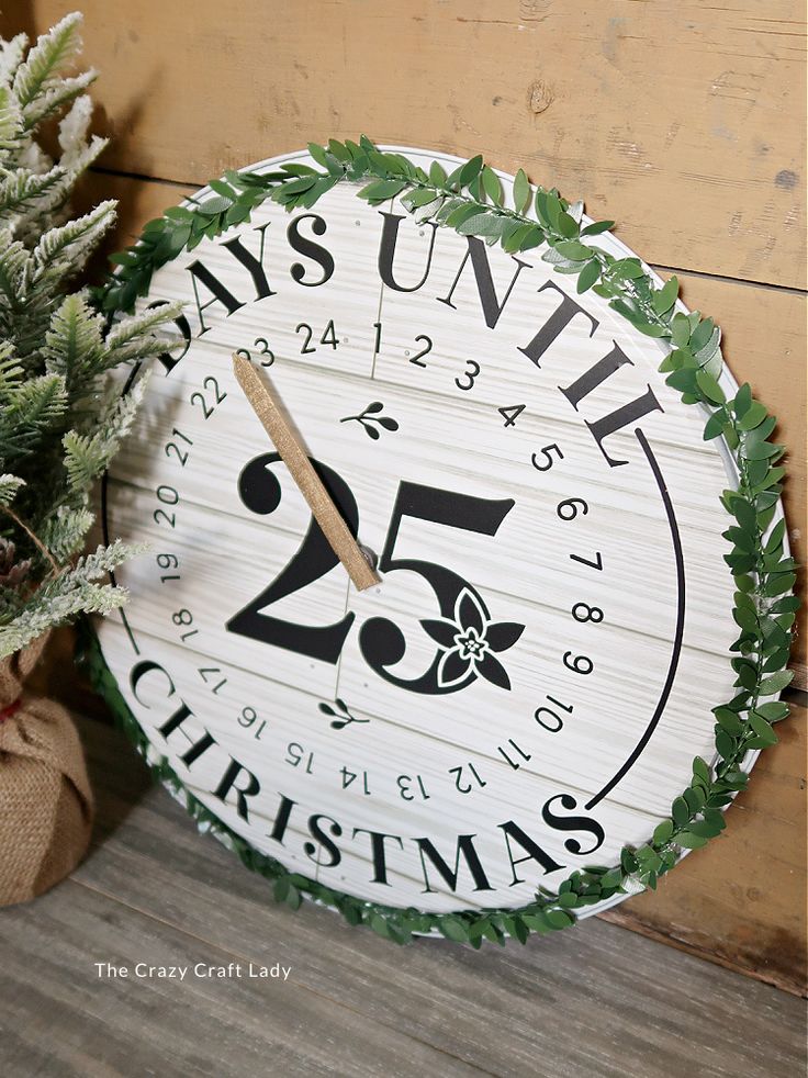 a wooden clock sitting next to a potted plant on top of a wood floor