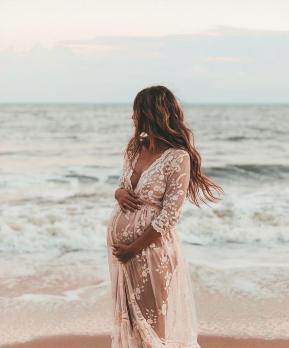 a pregnant woman standing on the beach