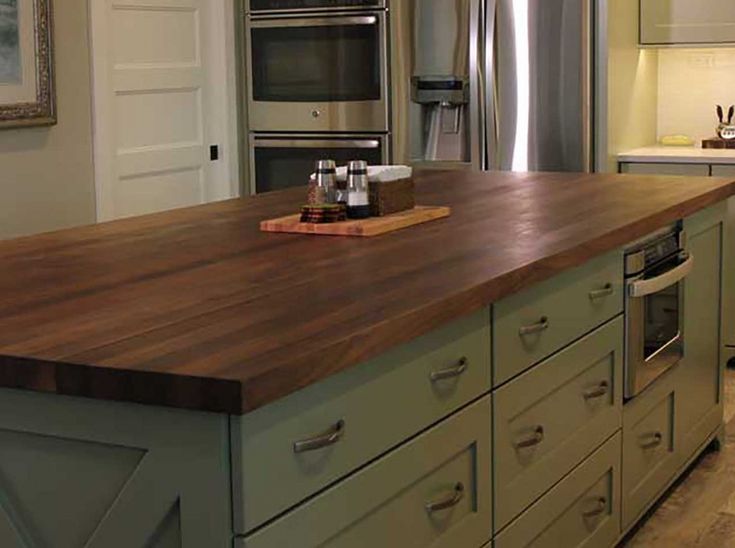 a kitchen with an island and stainless steel appliances in the center, along with wooden counter tops