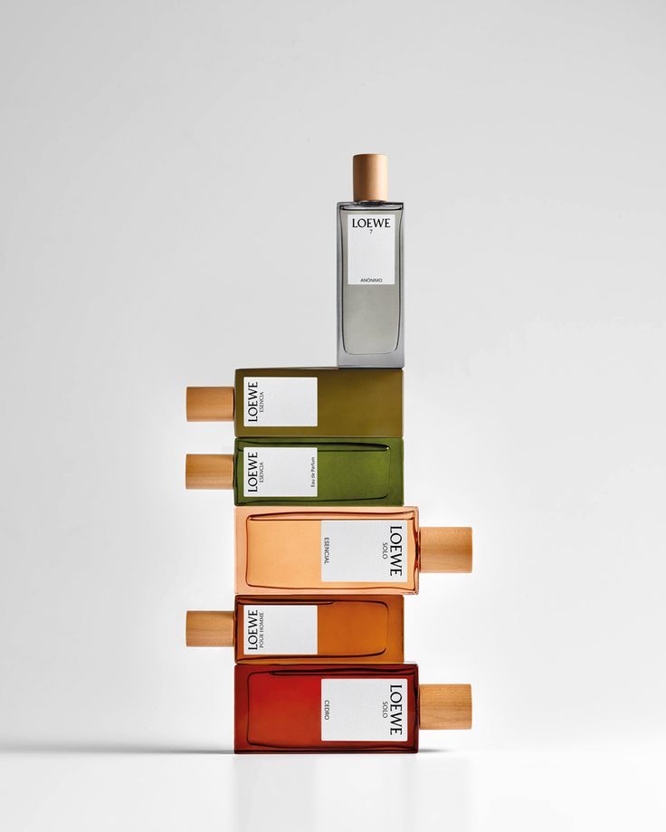 an assortment of perfumes stacked on top of each other in front of a white background