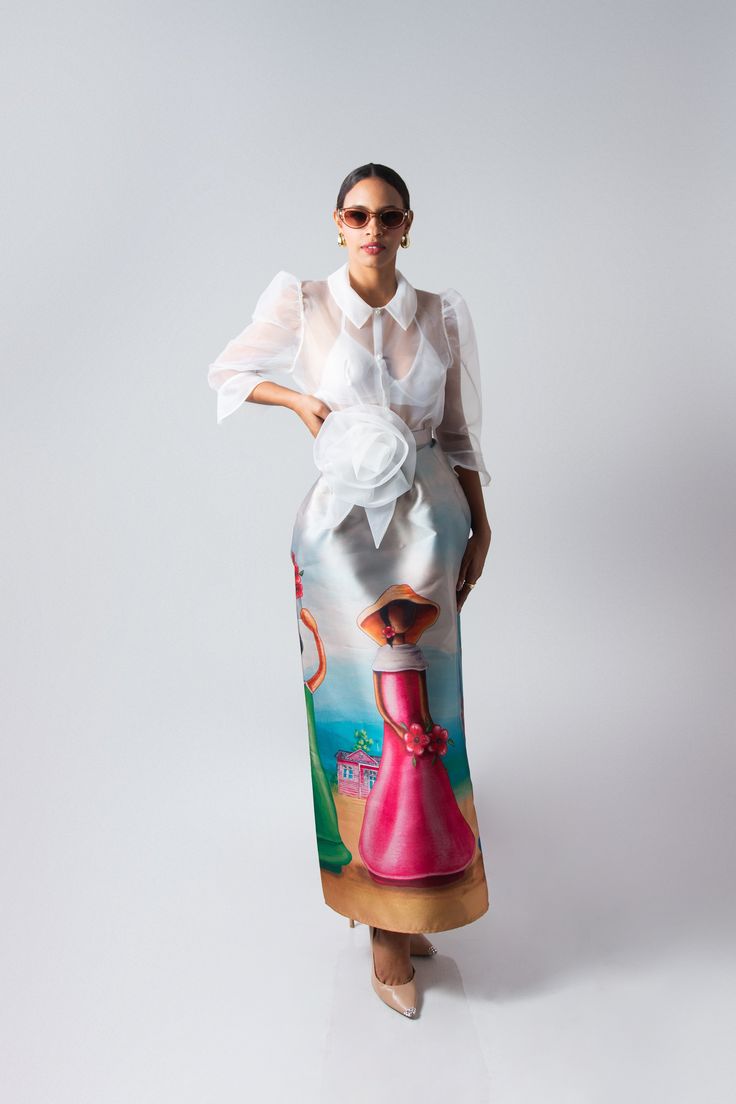 Flor de Caribe is a stunning long skirt crafted from luxurious mikado fabric, known for its rich texture and subtle sheen. The skirt features a full and graceful A-line silhouette, draping elegantly from the waist to the floor. Its standout detail is inspired by the traditional faceless dolls of the Dominican Republic. The artwork depicts these iconic figures, symbolizing Dominican heritage and culture, with soft, flowing lines and vibrant colors that stand out against the smooth surface of the Dominican Faceless Dolls, Spring Formal Floor-length Skirt, Spring Evening Silk Maxi Skirt, Luxury Long Skirt For Party, Luxury Flared Party Skirt, Chic Silk Skirt For Wedding, Luxury Flared Skirt For Party, Chic Silk Wedding Skirt, Formal Satin Pencil Skirt