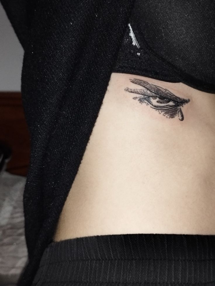 a woman's stomach with an eye tattoo on it