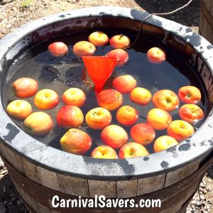 a bucket full of water filled with lots of apples and an orange cone sticking out of it