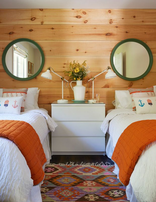 two beds in a room with wood paneling and mirrors on the wall above them