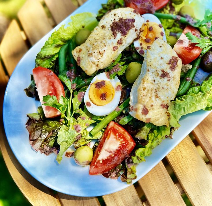 a white plate topped with salad and an egg