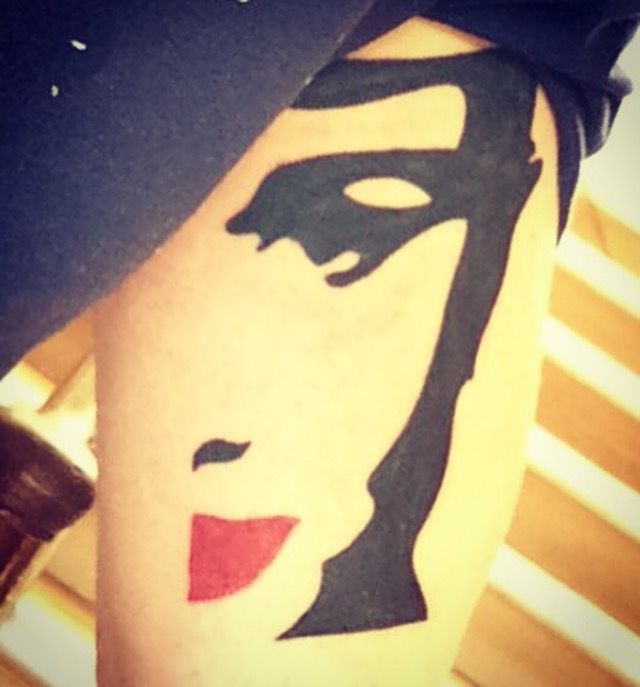 a woman's face is painted on the side of her leg with red lipstick