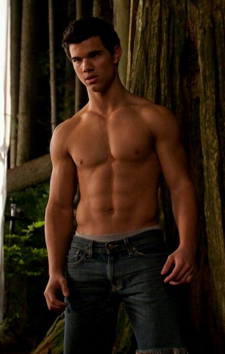 a shirtless man standing in front of a tree