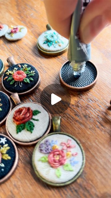 someone is using scissors to sew embroidered flowers on small coasters that are sitting on a table