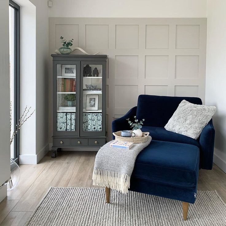 a living room with a blue couch and glass cabinet in the corner next to it