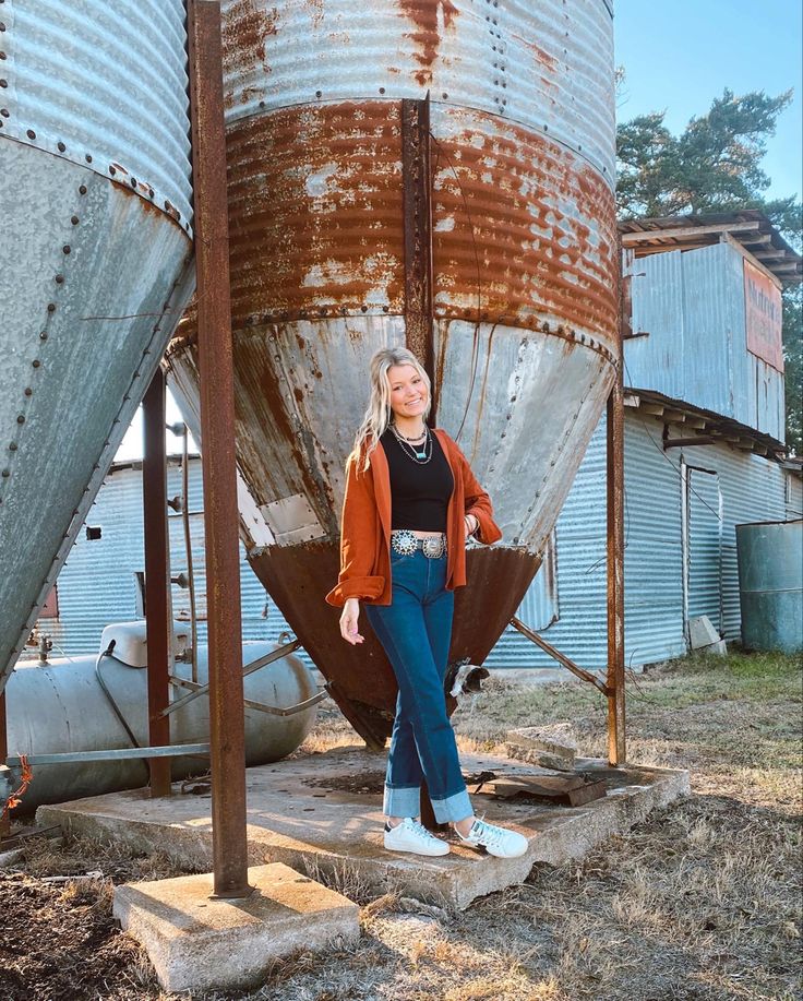 a woman standing in front of an old grain silo