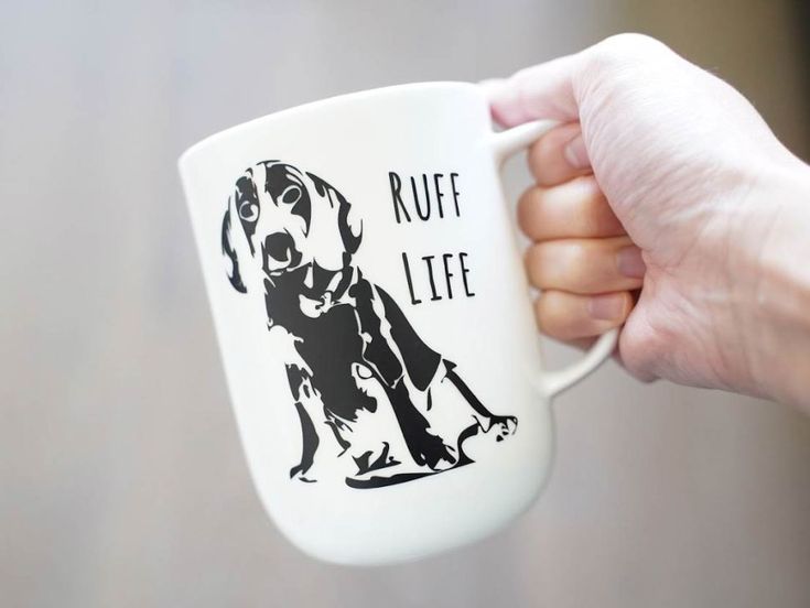 a person holding a coffee mug with a dog on it's side and the words ruff life printed on it