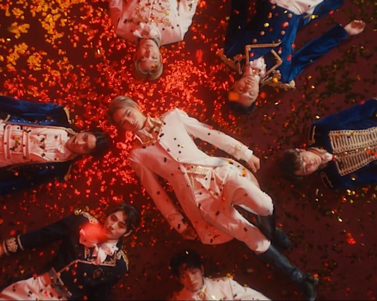 several people dressed in white and red confetti on the ground with one person laying down