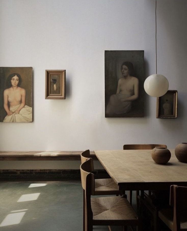 three paintings hang on the wall next to a table with chairs in front of it