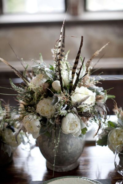 a vase filled with white flowers sitting on top of a wooden table next to plates