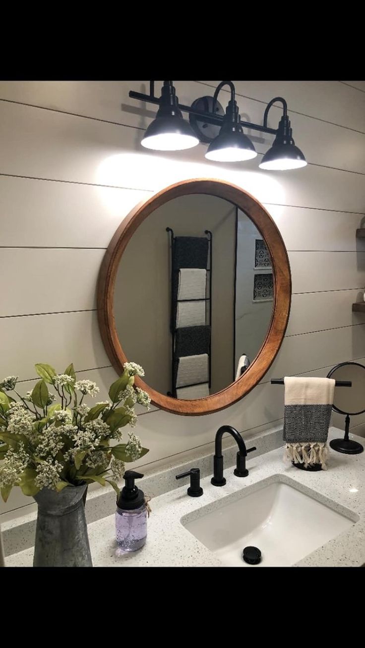 a bathroom sink with a round mirror above it