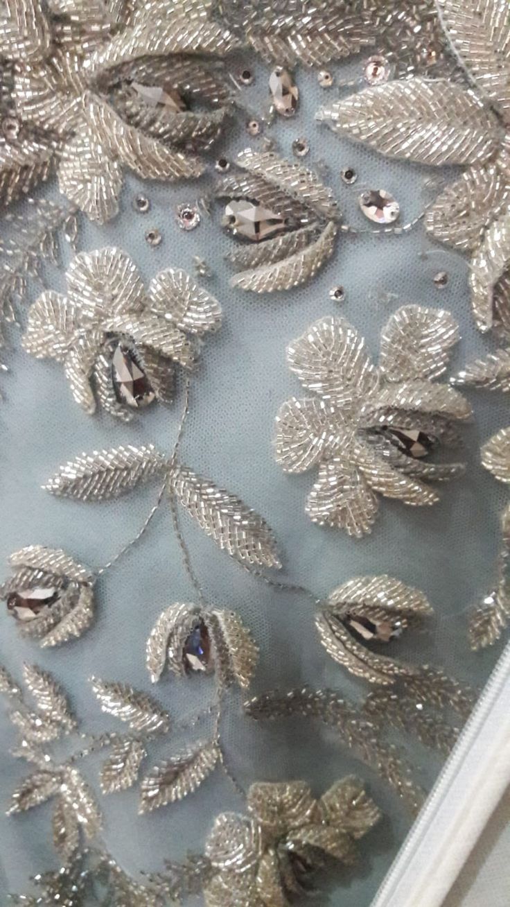 an embroidered fabric with silver sequins and leaves