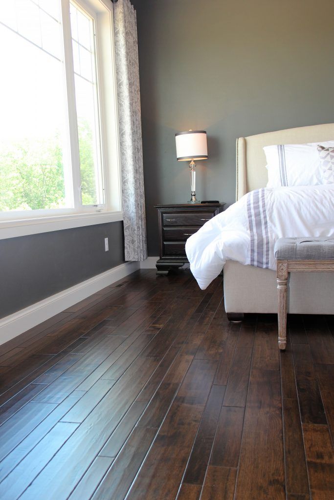 a bed sitting on top of a hard wood floor next to a window in a bedroom