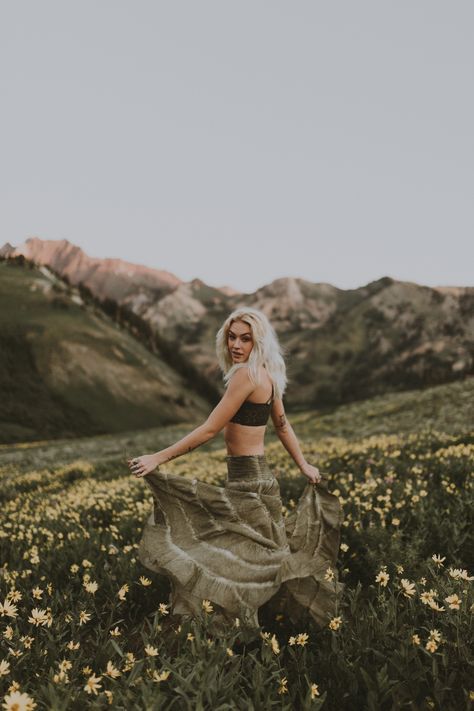 a woman is standing in a field with flowers