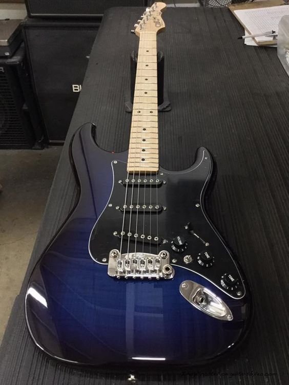 a blue electric guitar sitting on top of a black table next to other musical equipment