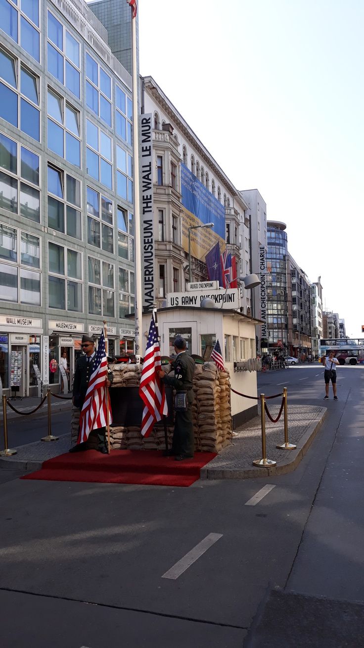 two men are standing in front of a building with an american flag on the ground