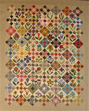 an old quilt with many different colors and designs on the front, along with small flowers