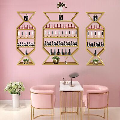 two pink chairs sitting next to a table in front of a wall mounted wine rack