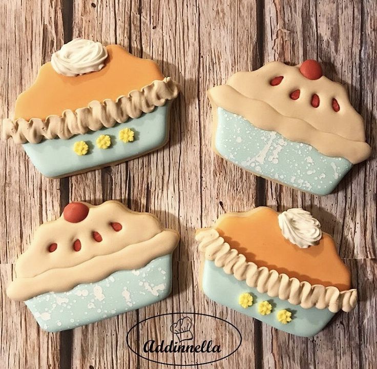 four decorated cookies sitting on top of a wooden table with frosting and icing