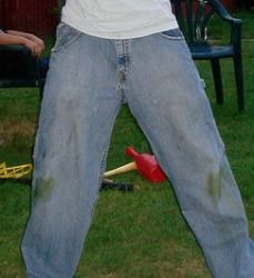 a man standing in the grass with his hands behind his back, holding a baseball bat