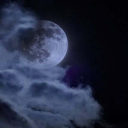 the full moon is seen through some clouds