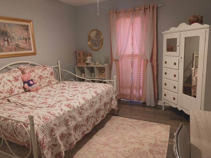 a bedroom with a bed, dresser and pink curtained window in the corner on the far wall