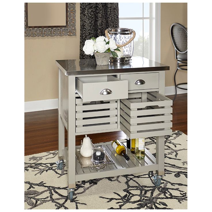 a kitchen island with two drawers and wine bottles on the bottom shelf, in front of a window