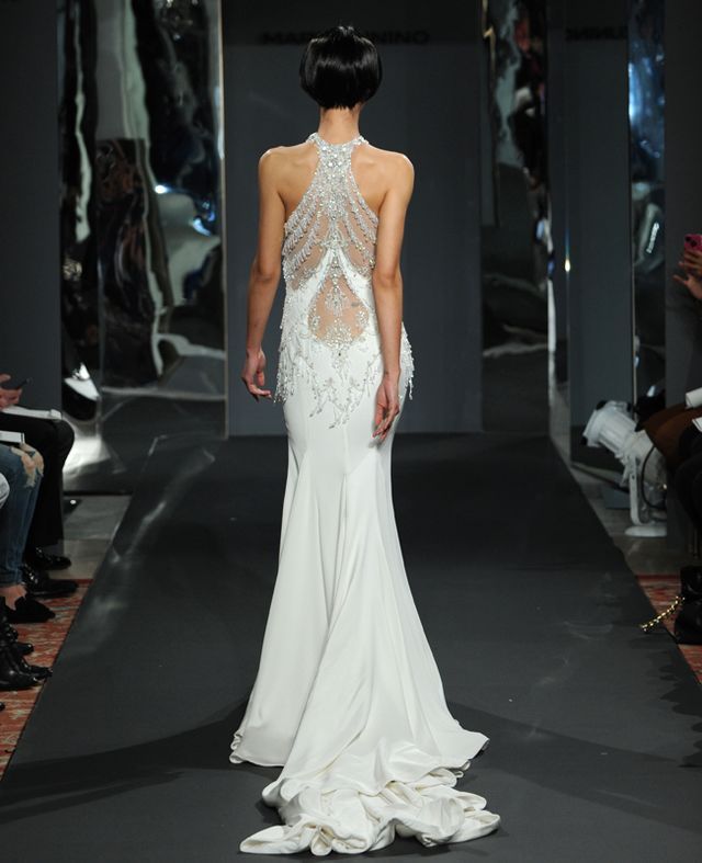 a woman is walking down the runway wearing a white dress with beading on it