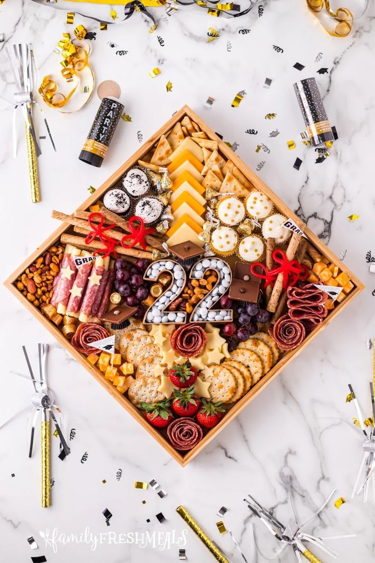 a wooden box filled with lots of different types of snacks and confetti on top of a marble table