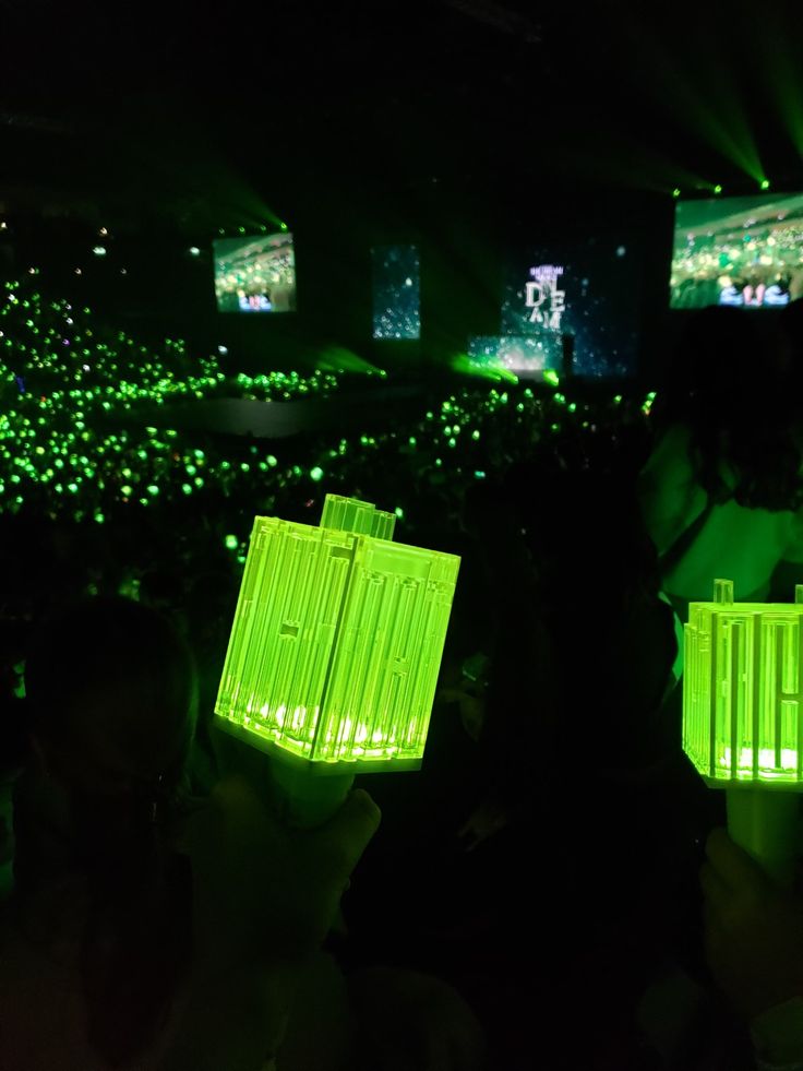 two people holding up their cell phones in the dark with green lights shining on them