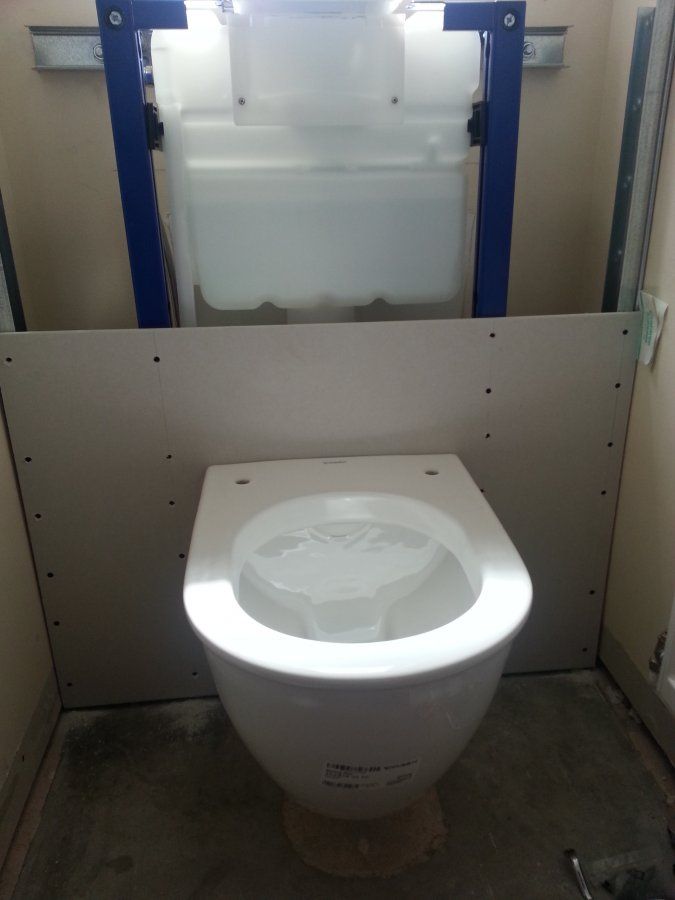 a white toilet sitting inside of a bathroom next to a wall with blue bars on it