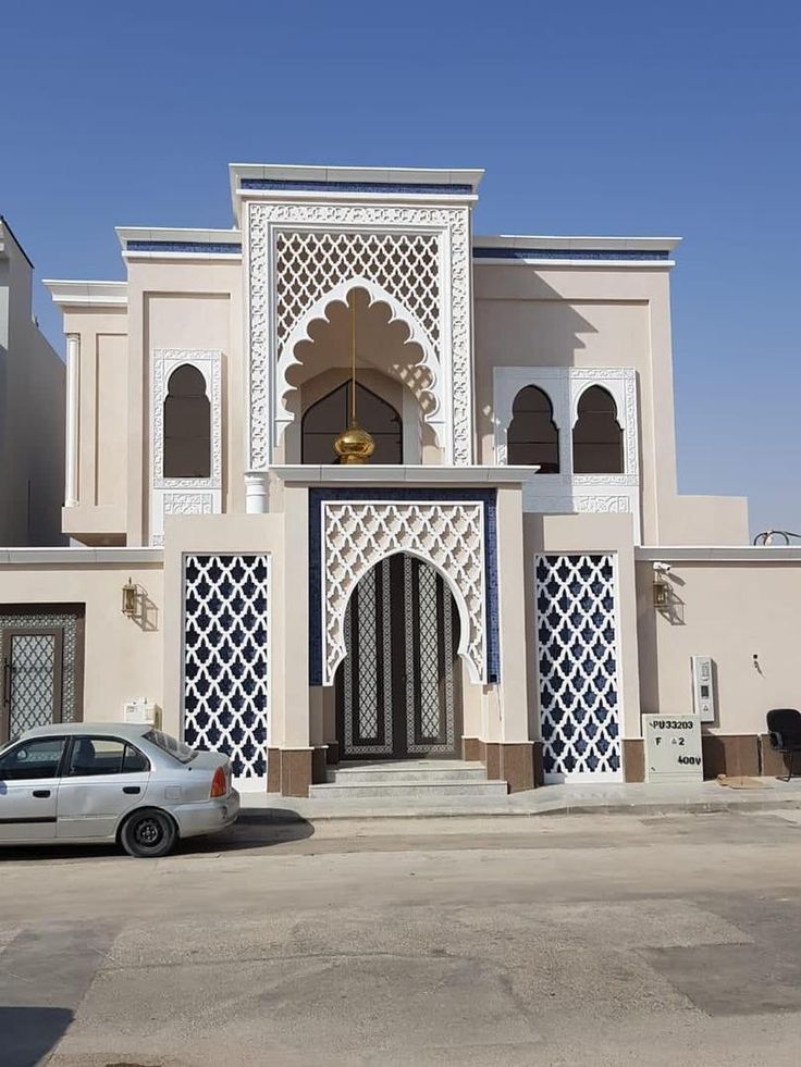 a white car parked in front of a large building with arches and doorways on it