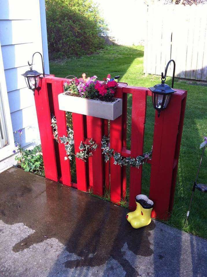 a red wooden fence with flowers growing out of it and the words solar lights on shepards hooks do you like it??