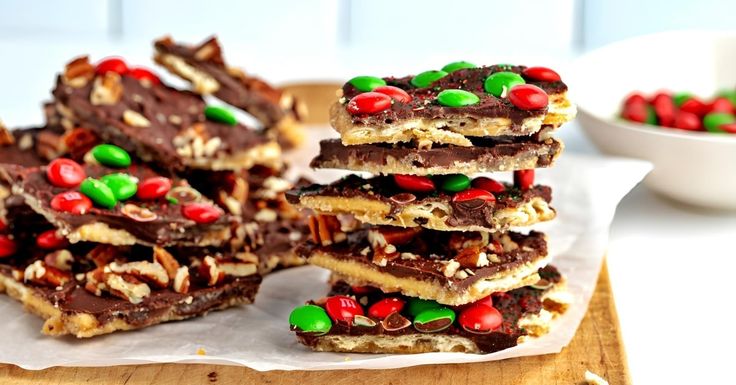 several pieces of chocolate barkle with candy and candies in the middle on a wooden cutting board