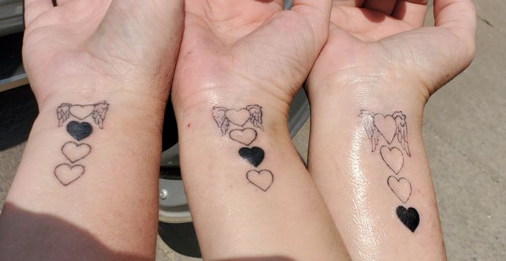 two girls with matching tattoos on their arms holding hands in the shape of heart shapes