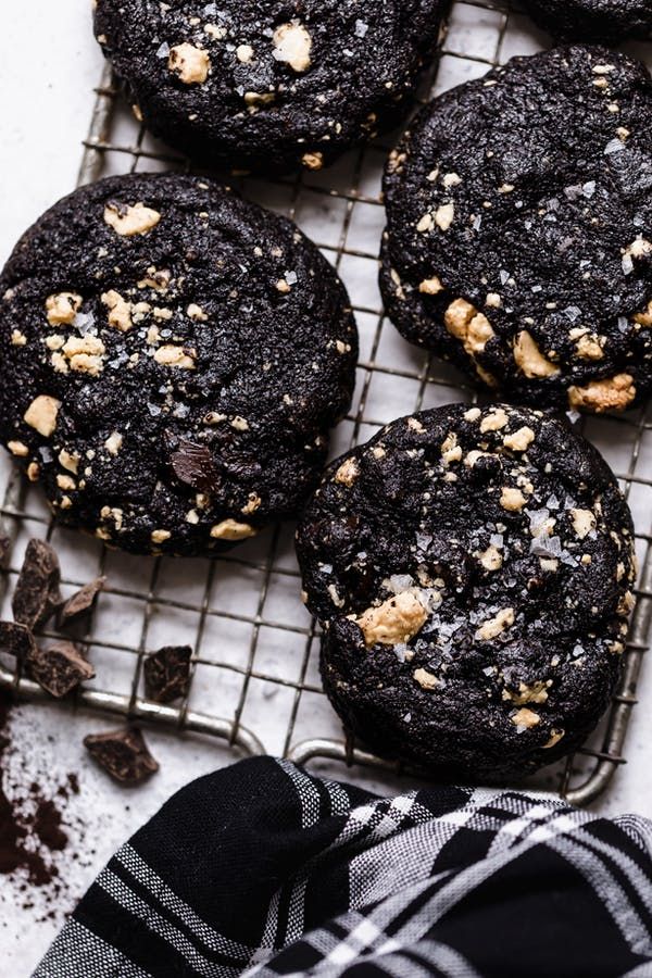 chocolate cookies with walnuts on a cooling rack next to a black and white towel