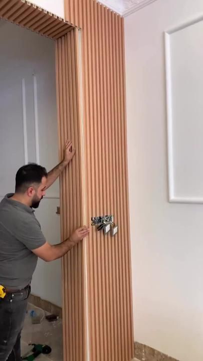 a man that is standing in front of a wall with some screws on it