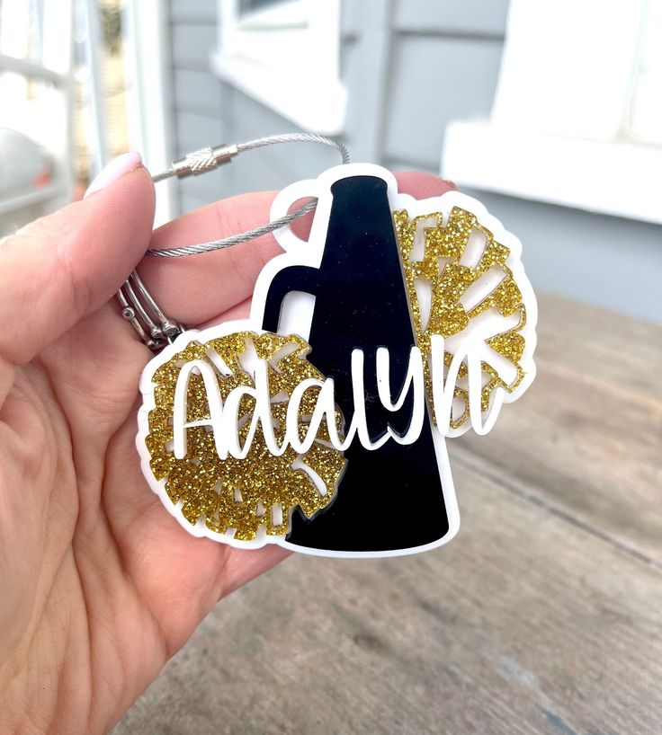 a hand holding a black and gold keychain with the word avault on it