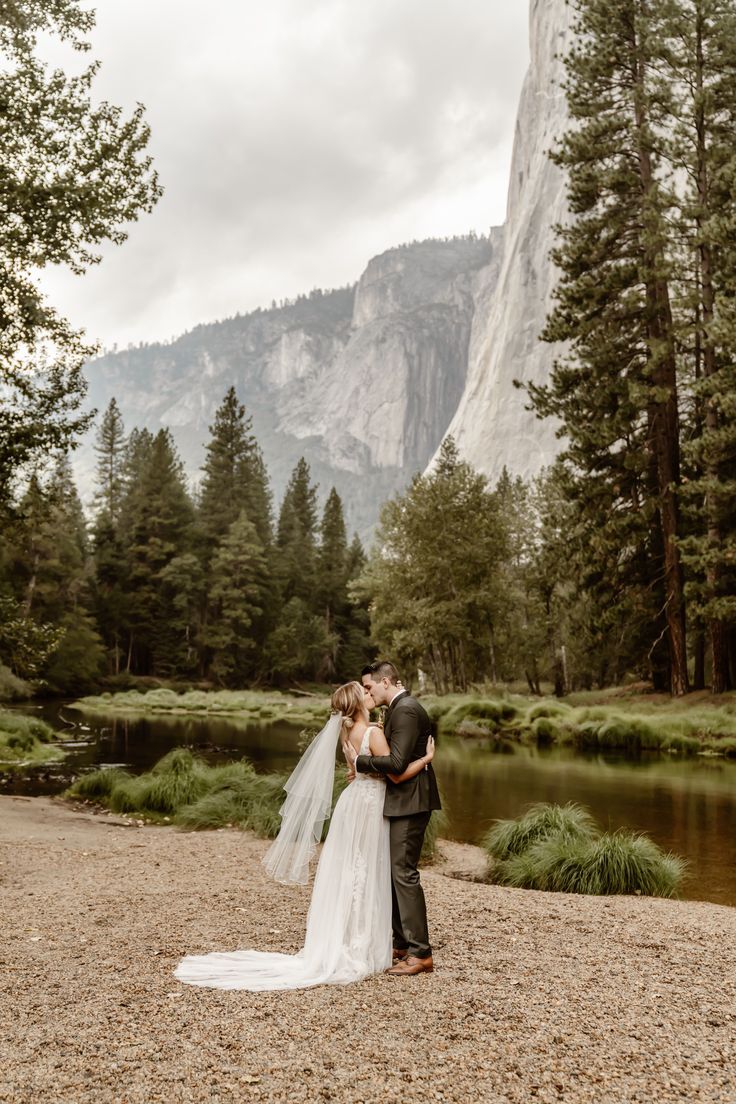 a bride and groom standing in front of a mountain