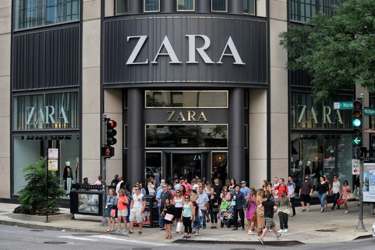 a group of people standing in front of a zara store on a city street