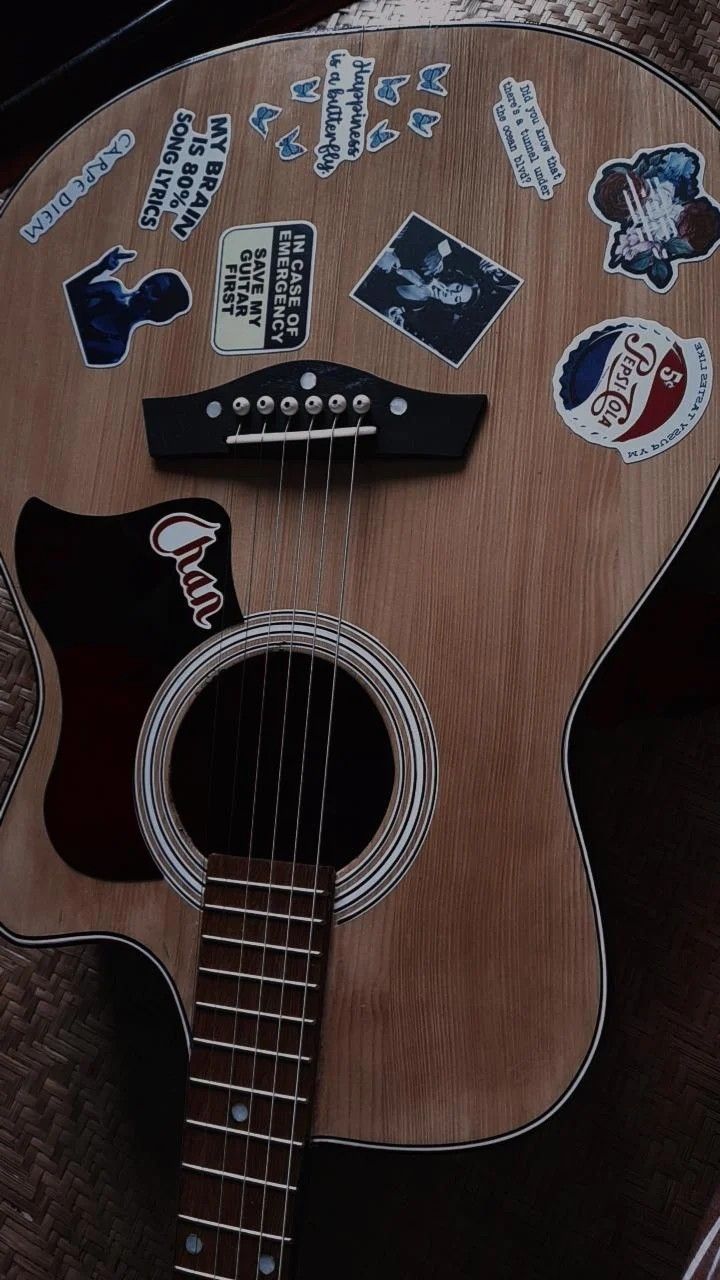 an acoustic guitar with stickers on it