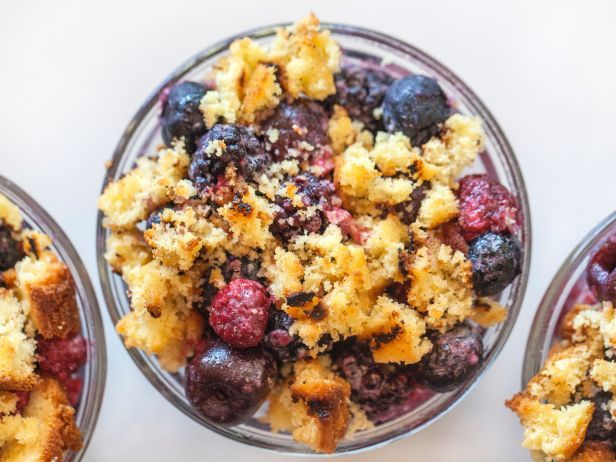 three bowls filled with fruit and crumbs on top of a white tablecloth