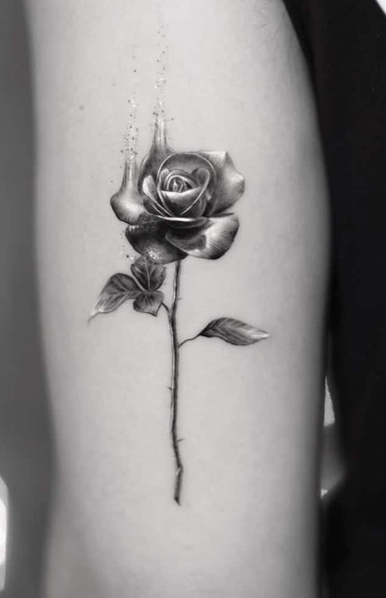 a black and white photo of a rose on the thigh