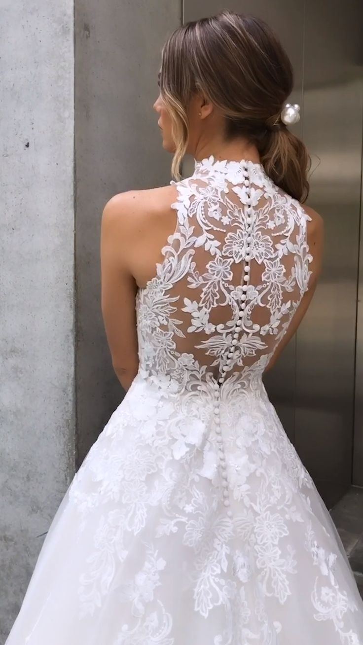 a woman in a white wedding dress standing next to an open door with her back turned towards the camera