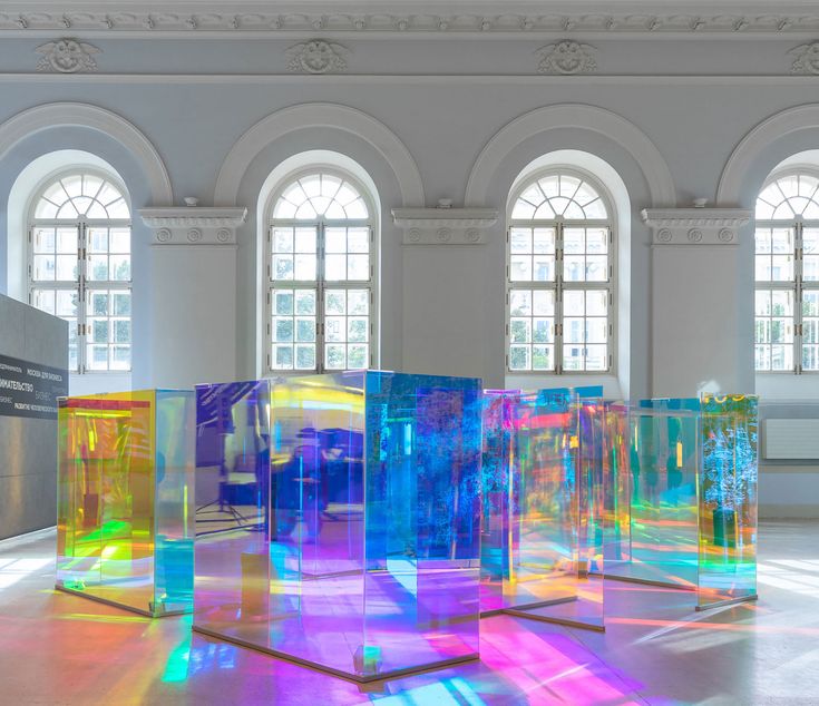 an art installation with multiple colored glass blocks in front of two large arched windows on the wall