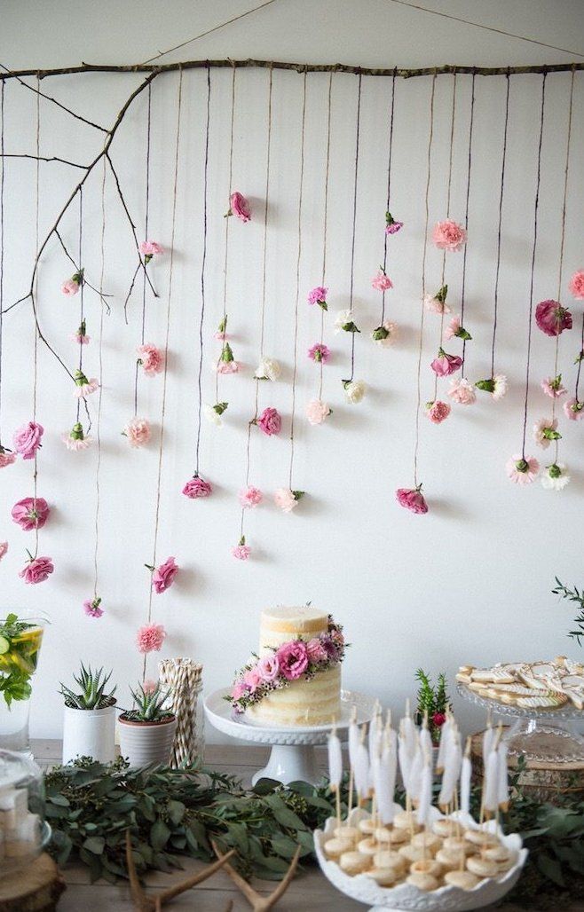 a table topped with cakes and desserts covered in pink flowers hanging from the ceiling